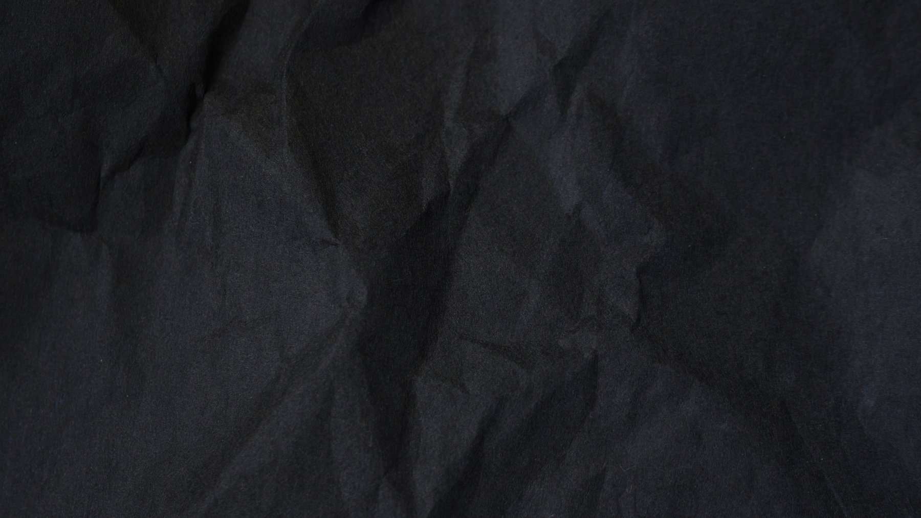 Dark abstract textile background texture. Black crumbled paper texture.